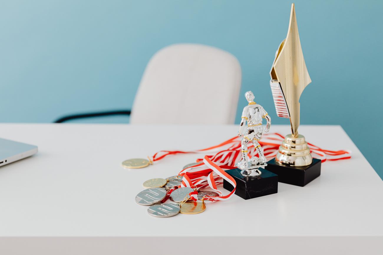 Colección de trofeos y medallas sobre un escritorio blanco, simbolizando el éxito y la victoria en los rangos.