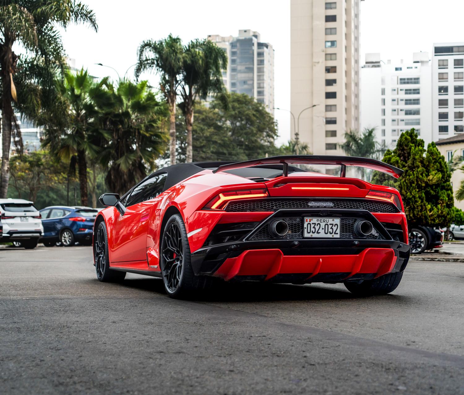 Coche deportivo de lujo rojo estacionado en una calle urbana con palmeras, reflejando la opulencia de Los Santos.