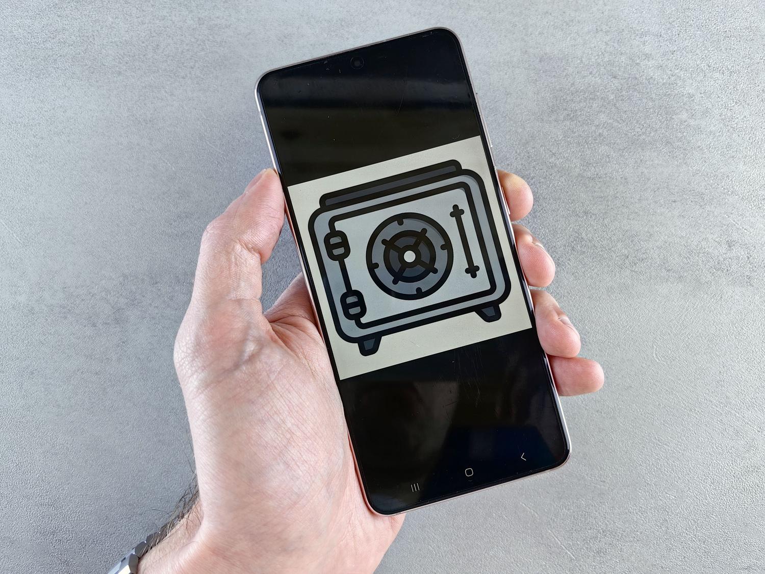 Pantalla de smartphone mostrando el icono de una caja fuerte, representando el cifrado de datos y la protección de la información personal.