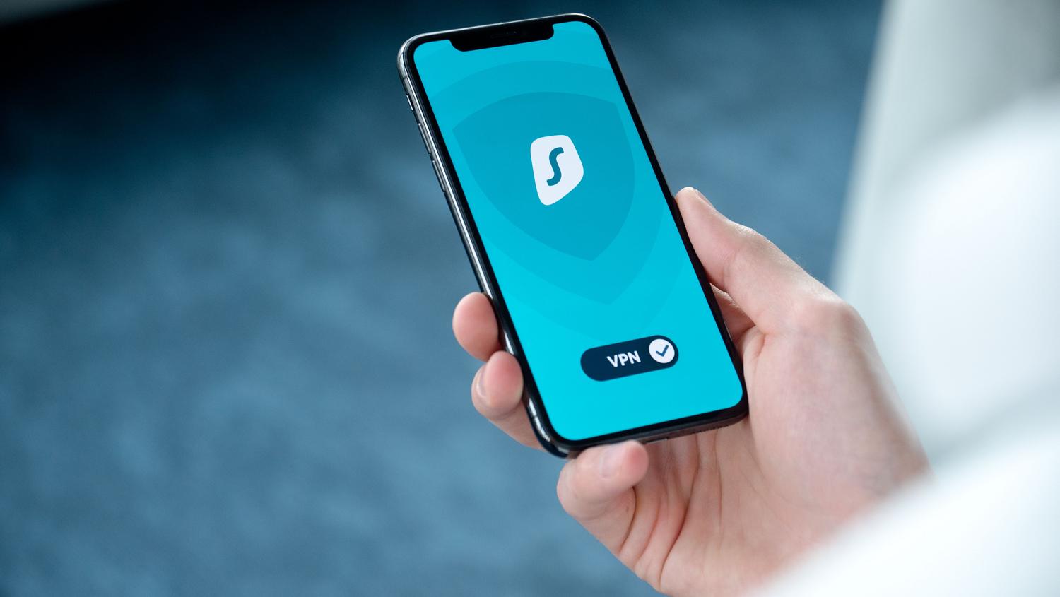 Primer plano de una mano sosteniendo un iPhone con una aplicación de VPN activada, mostrando el interruptor de conexión.