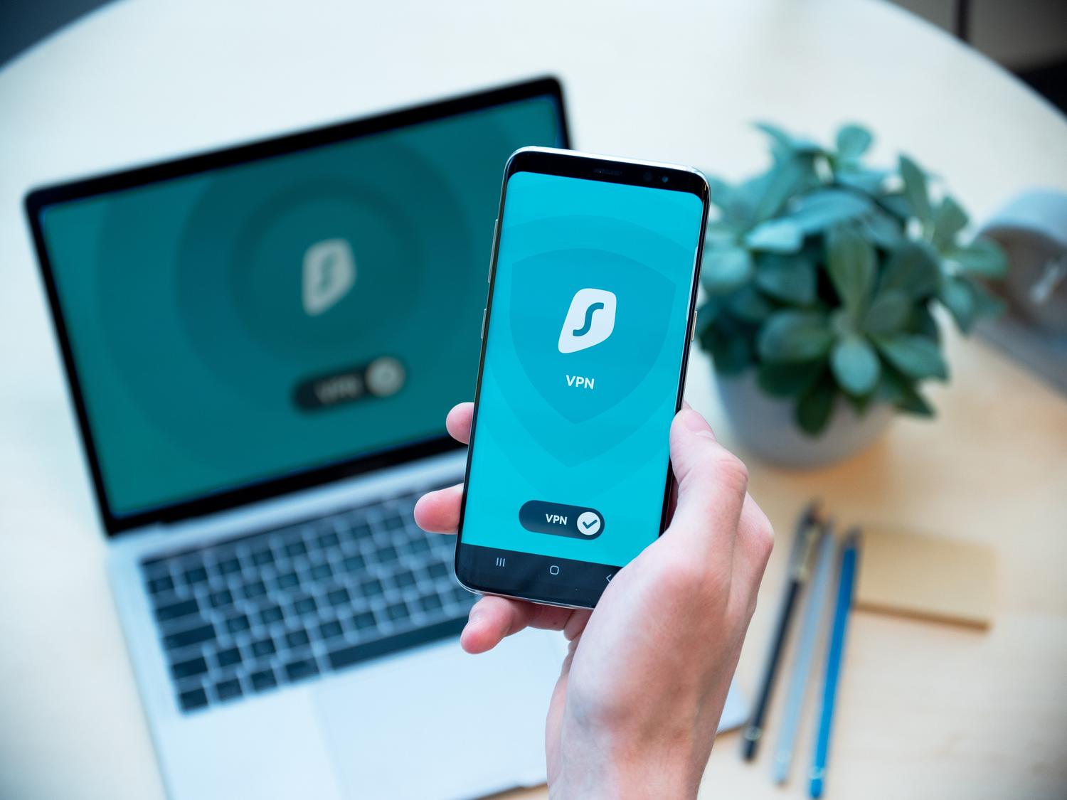 Configuración de VPN sincronizada entre un smartphone y un ordenador portátil en un espacio de trabajo moderno.