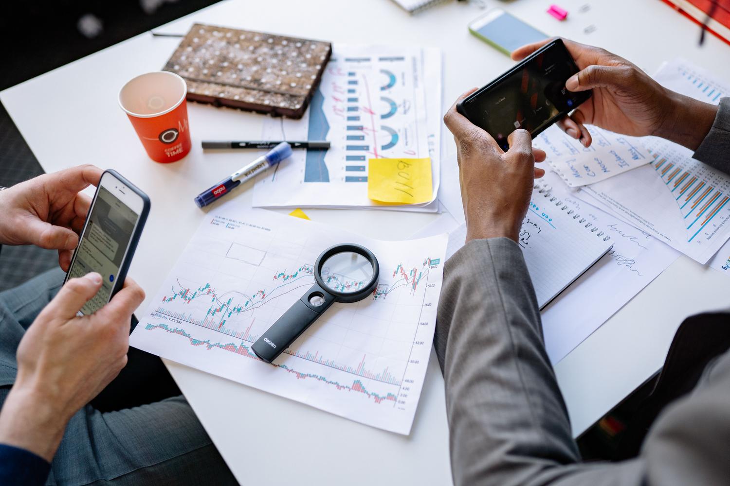 Dos profesionales analizando datos y gráficos en sus smartphones sobre una mesa, simbolizando el trabajo colaborativo y el uso de herramientas CRM.