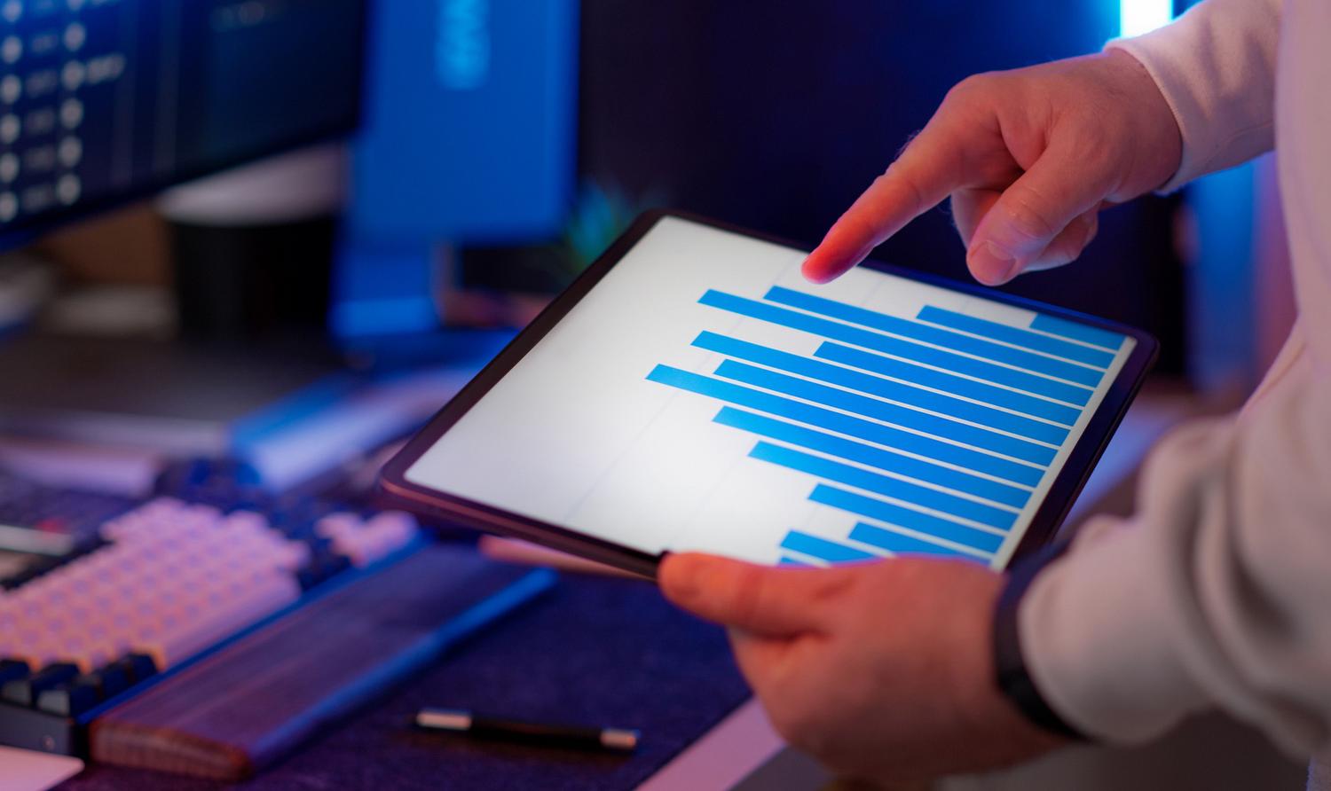 Profesional analizando datos financieros en una tablet en un entorno de oficina moderno.