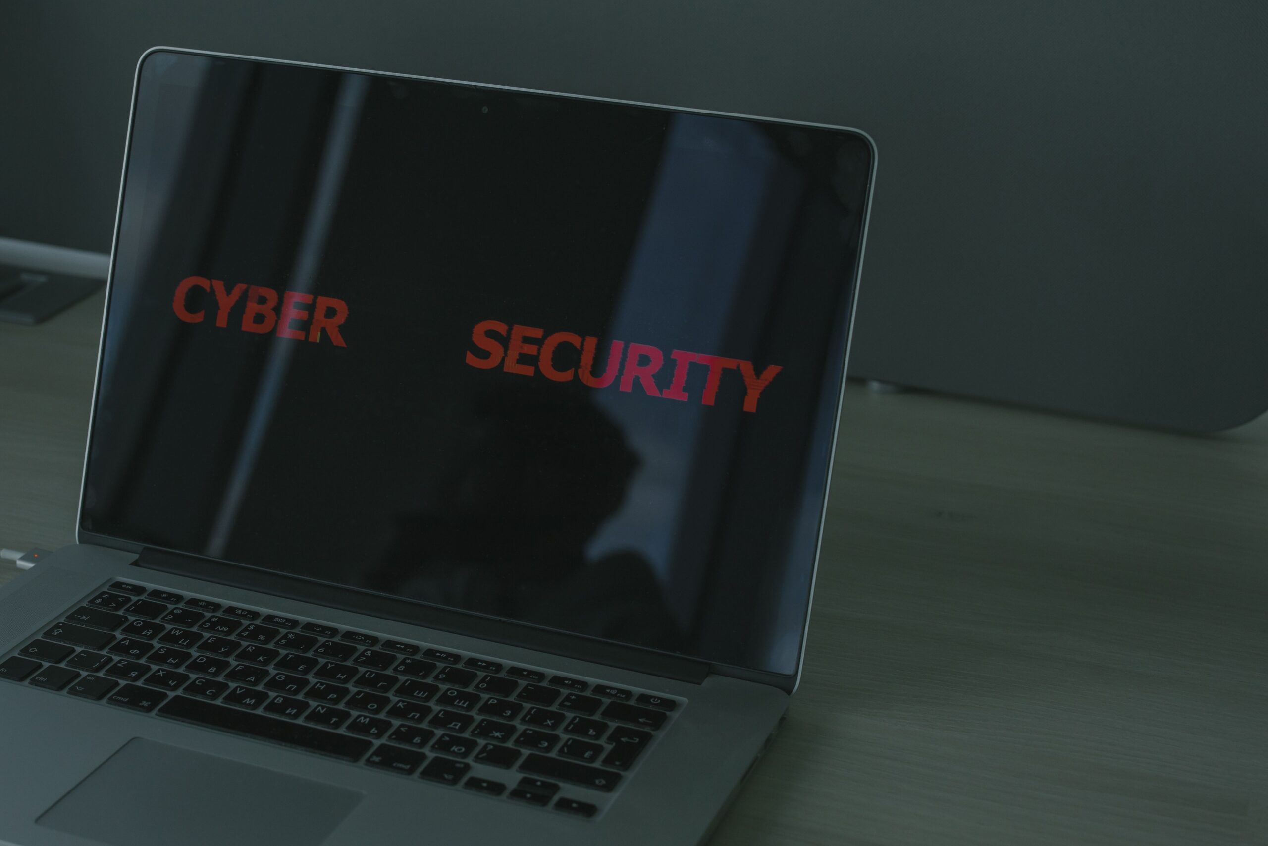 Detalle de pantalla de portátil con el texto CYBER SECURITY en rojo, reforzando la temática de seguridad digital.