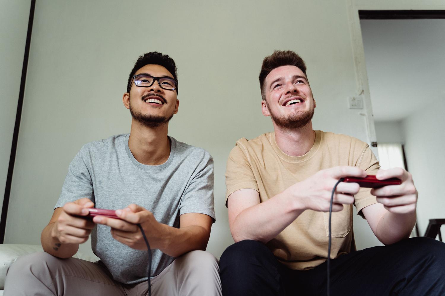 Dos hombres jugando videojuegos alegremente en un salón moderno.