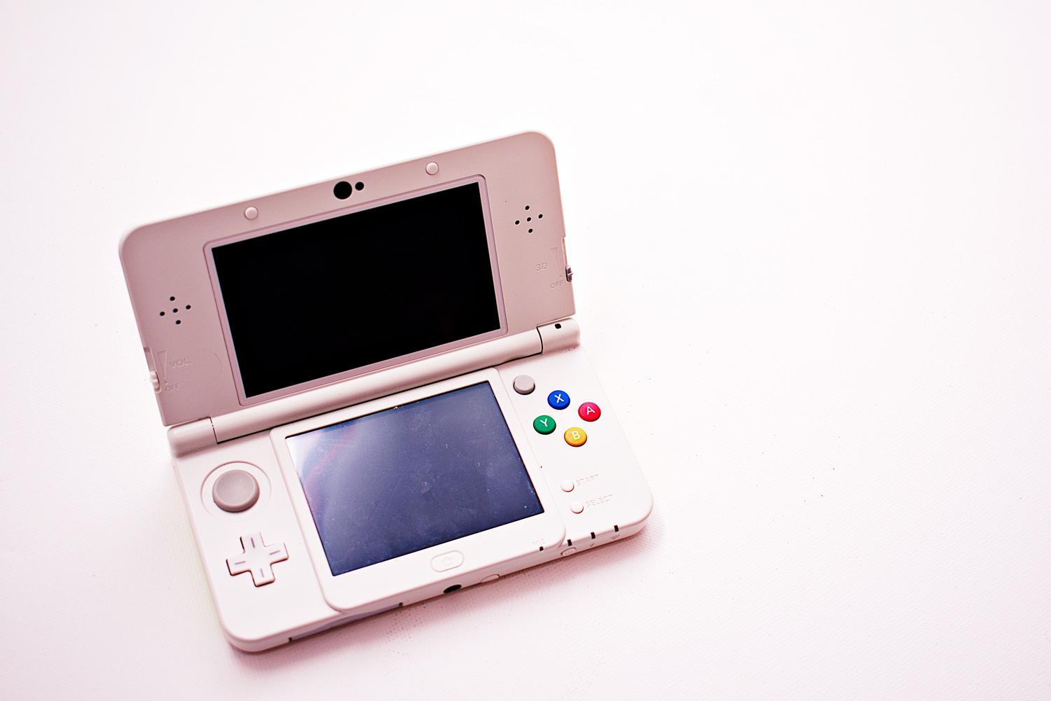 Primer plano de una consola Nintendo 3DS blanca, dispositivo emblemático para diversas generaciones de juegos Pokémon. Primer plano de una consola Nintendo 3DS blanca, dispositivo emblemático para diversas generaciones de juegos Pokémon.