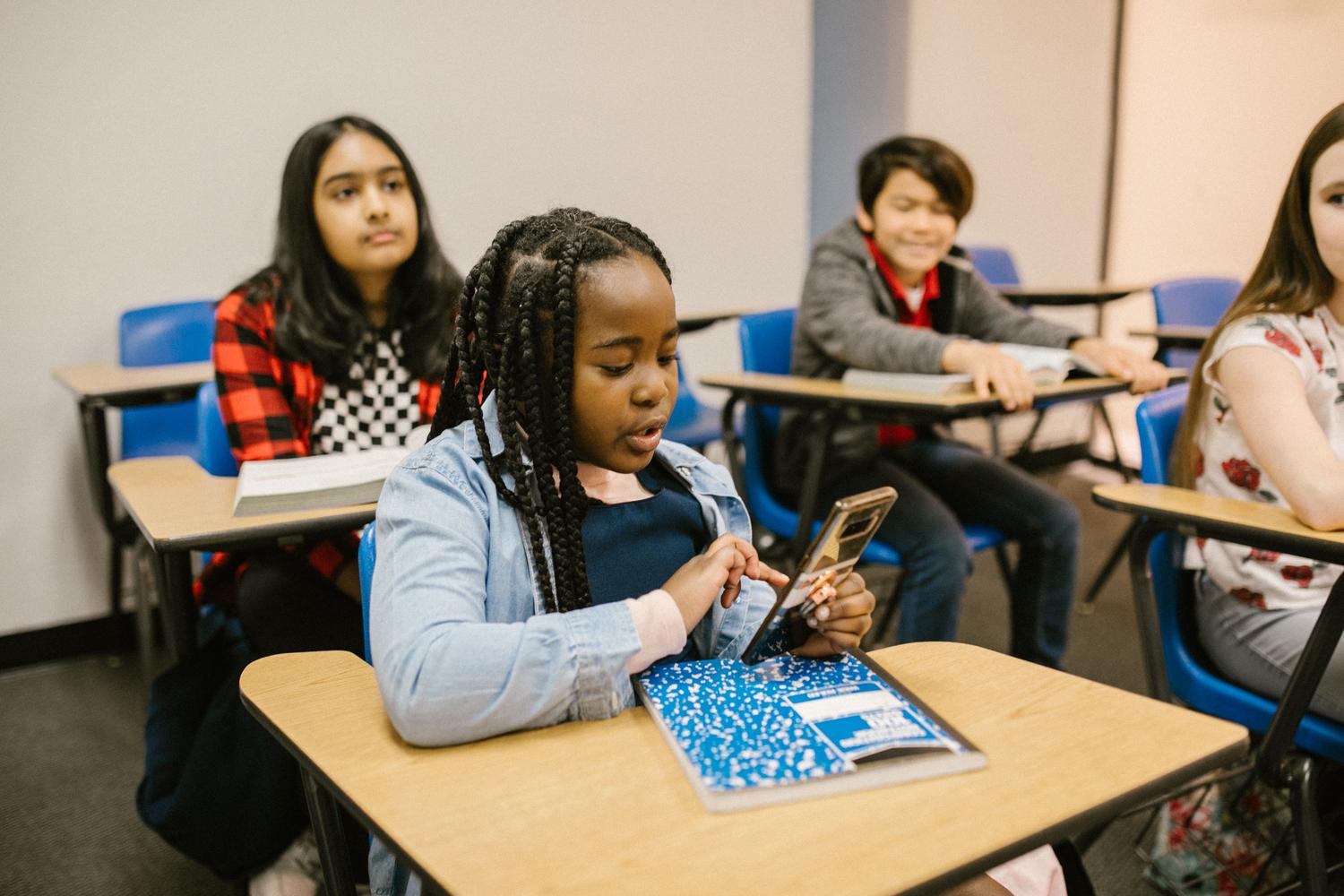 Estudiante concentrada realizando una tarea escolar digital en su propio dispositivo móvil.