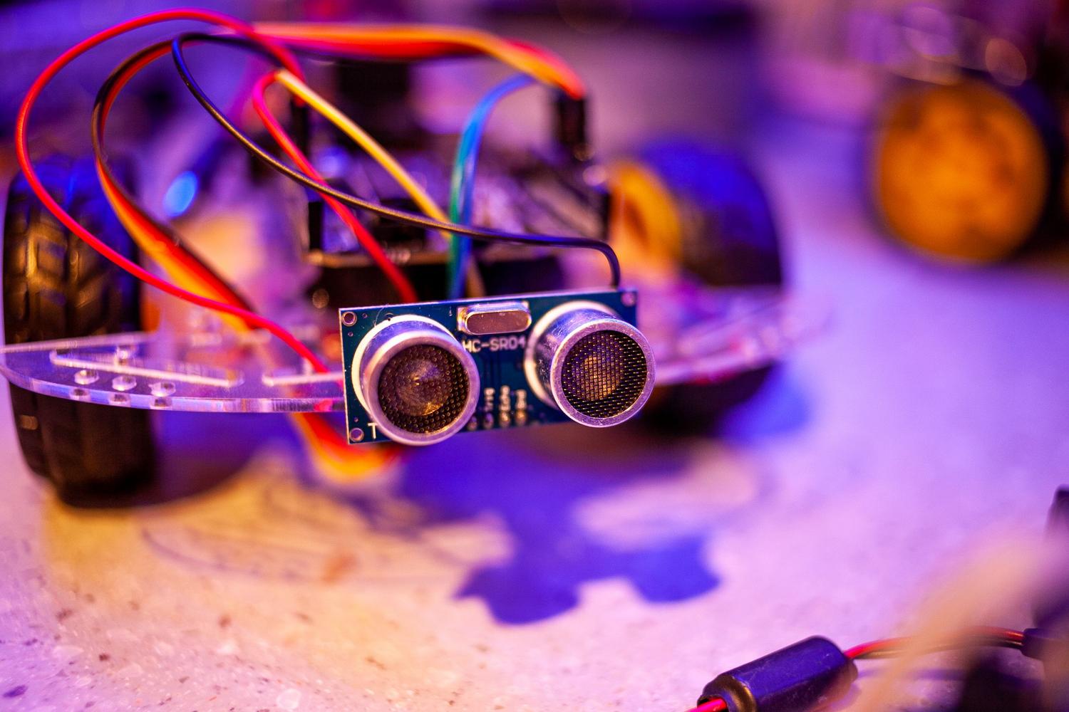 Primer plano de sensores ultrasónicos y cableado de un robot, ilustrando la percepción sensorial y la recogida de datos del entorno