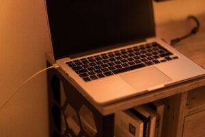 Portátil conectado a la corriente en un escritorio de madera con iluminación cálida