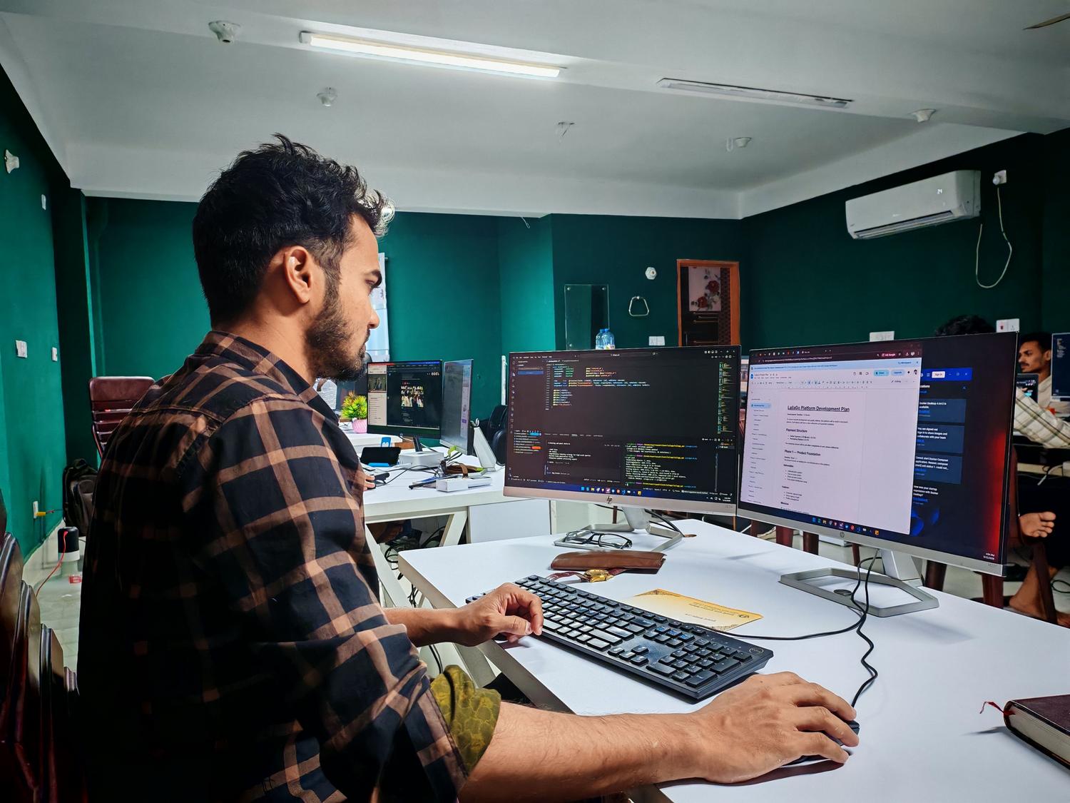 Entorno profesional de desarrollo con Firebase Entorno de trabajo profesional con doble monitor mostrando código y planificación de desarrollo de plataforma.