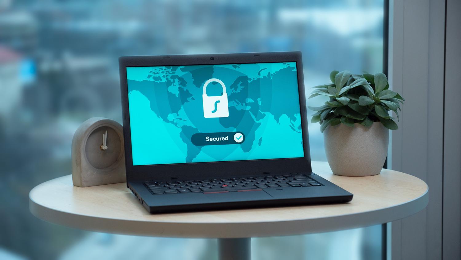 Portátil sobre una mesa mostrando un icono de candado y el mensaje 'Secured', ilustrando la protección de la privacidad digital.