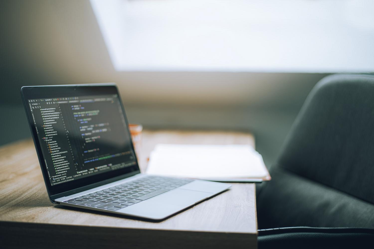 Espacio de trabajo moderno con un portátil mostrando código, ideal para representar la gestión de herramientas digitales en una pyme.