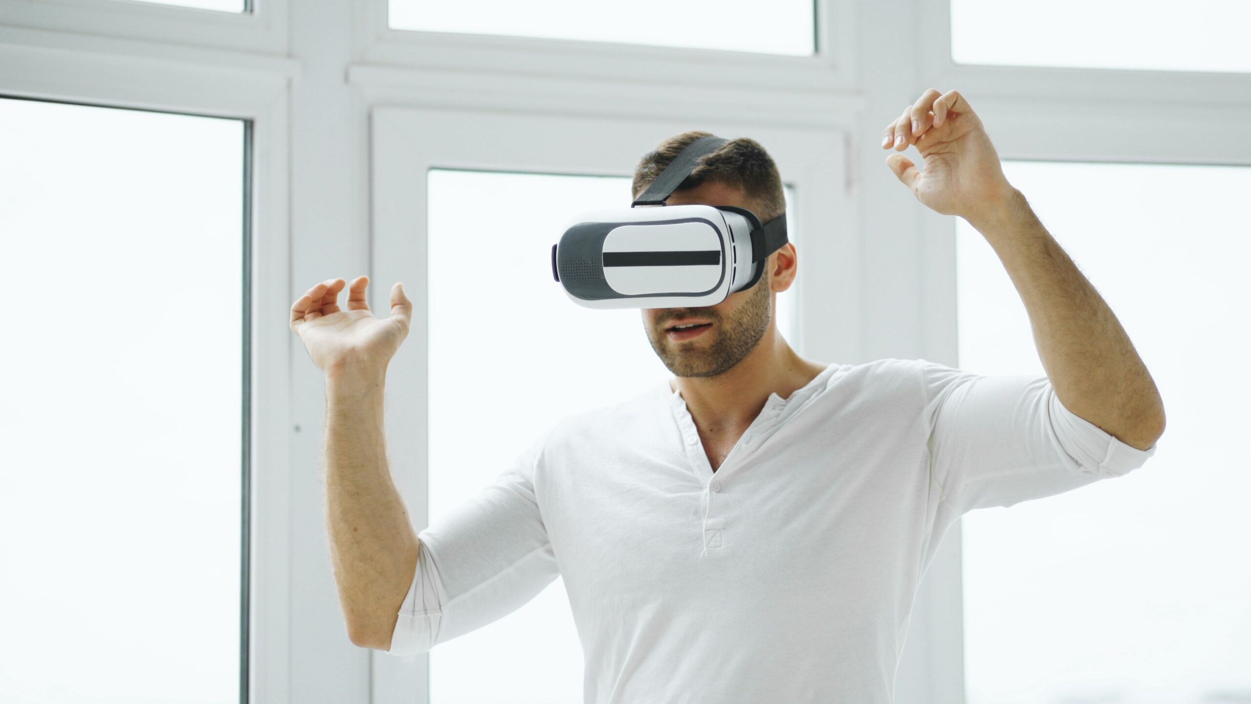 Hombre joven interactuando con un entorno virtual mediante un visor de VR en una habitación iluminada.