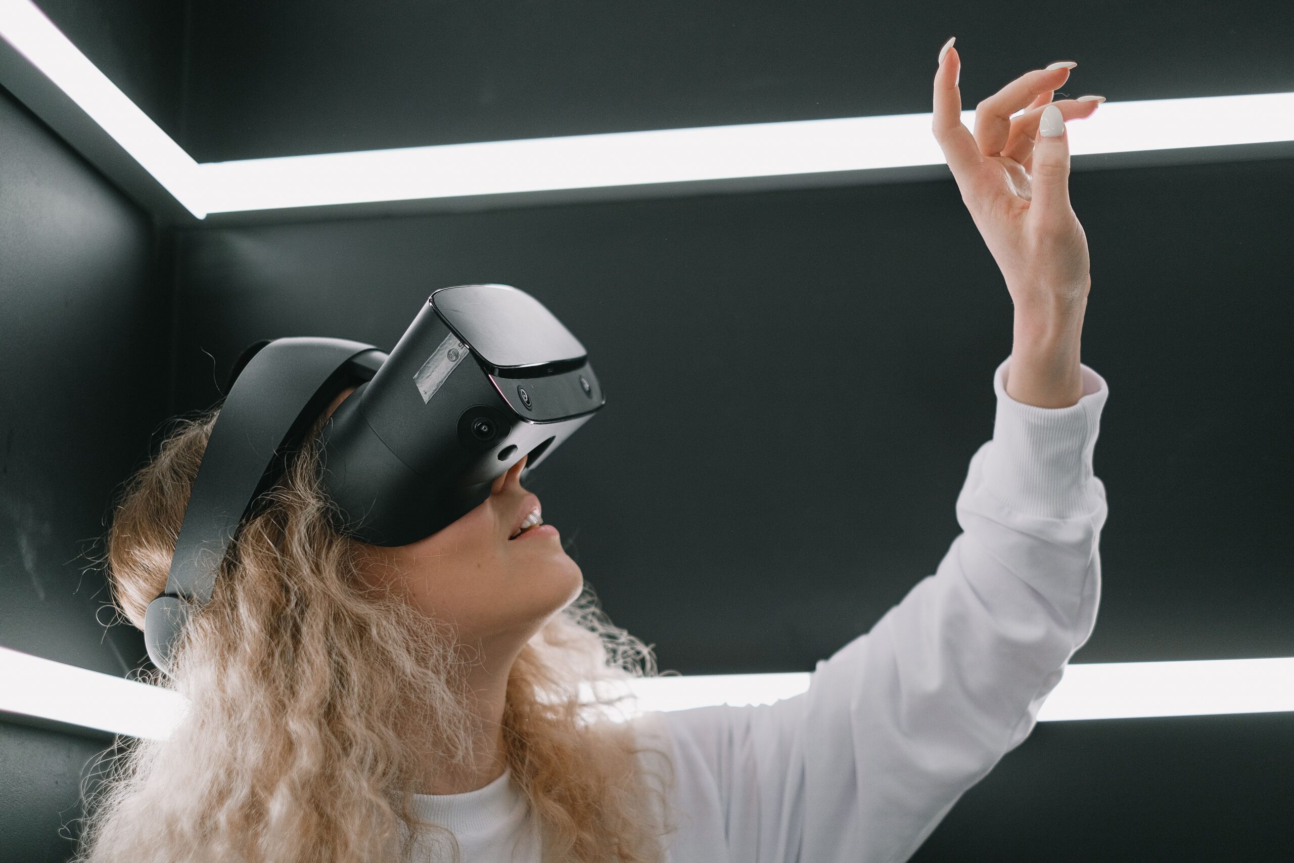 Mujer inmersa en una experiencia de VR en un espacio futurista con iluminación LED, simulando la interacción con objetos virtuales.