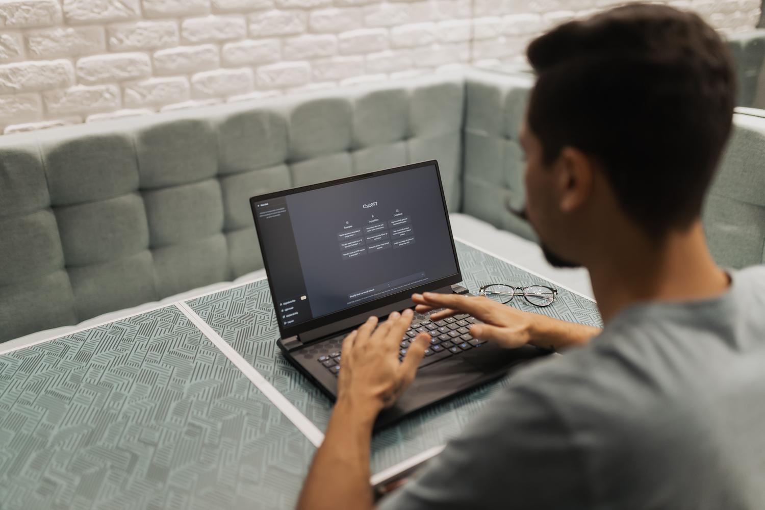 Hombre trabajando con un portátil en una oficina moderna, ilustrando la productividad impulsada por la IA y el uso de Copilots en el entorno empresarial.