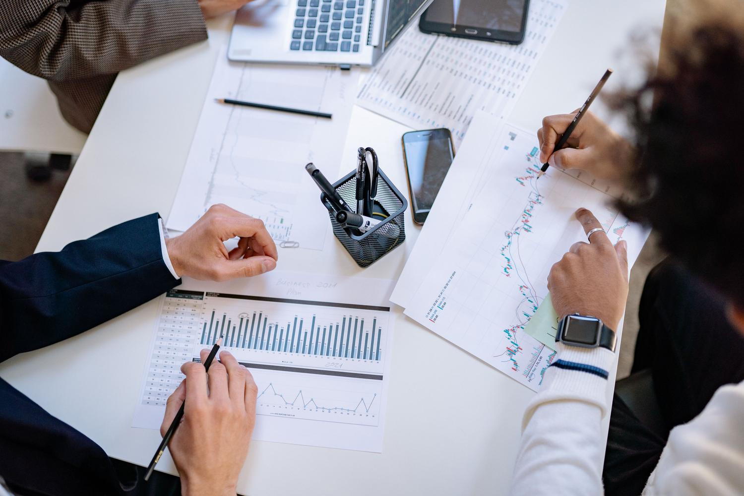 Equipo de negocios analizando gráficos financieros y datos en una reunión colaborativa, ejemplificando el impacto de la IA en las finanzas y la toma de decisiones.