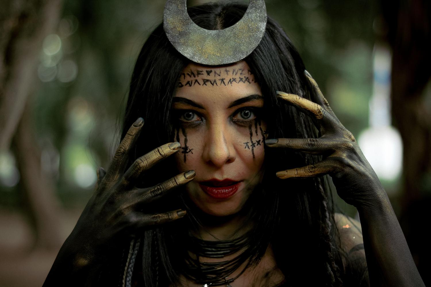Mujer mística con adornos rúnicos en un bosque oscuro, representando a las hechiceras y el arquetipo de Mago