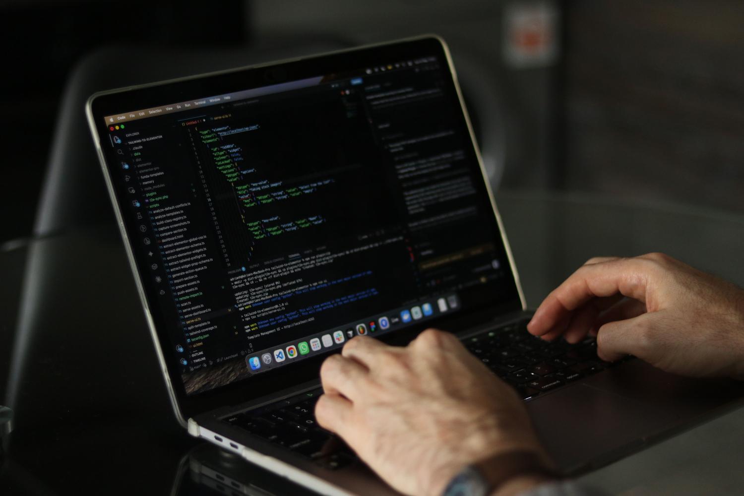 Primer plano de las manos de un desarrollador programando código en un portátil, ilustrando la creación de complementos con Apps Script