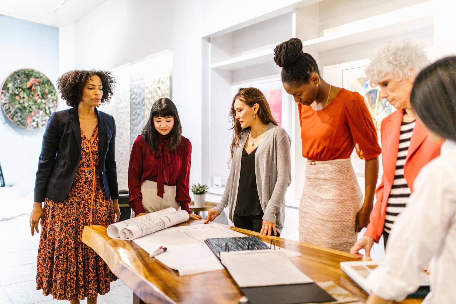 Grupo diverso de mujeres profesionales colaborando en una oficina moderna, ilustrando el talento y liderazgo sin sesgos de género