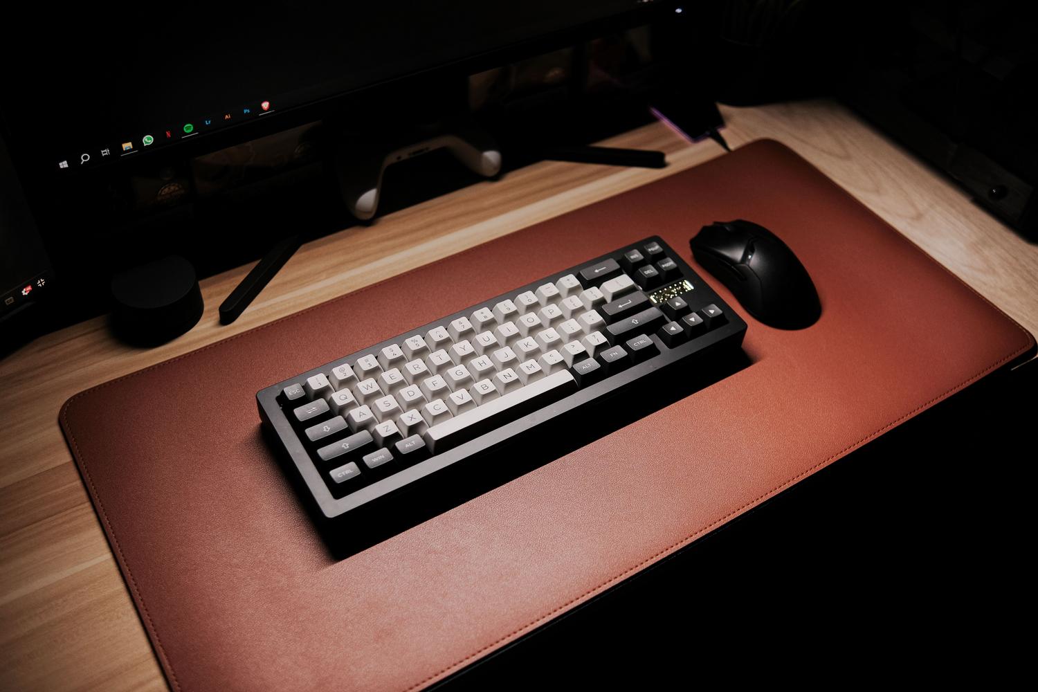 Teclado mecánico y ratón ergonómico sobre una alfombrilla, destacando la importancia de los periféricos de calidad en la productividad.