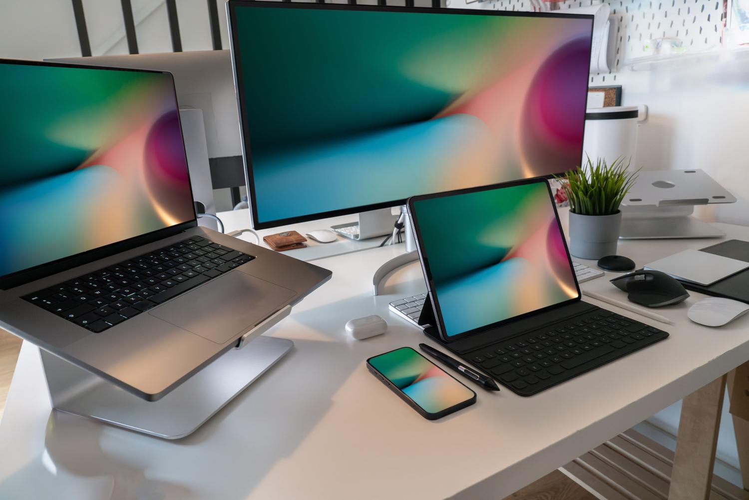 Espacio de trabajo contemporáneo con portátil, tableta, smartphone y monitor, representando el flujo de trabajo híbrido y el ecosistema tecnológico.