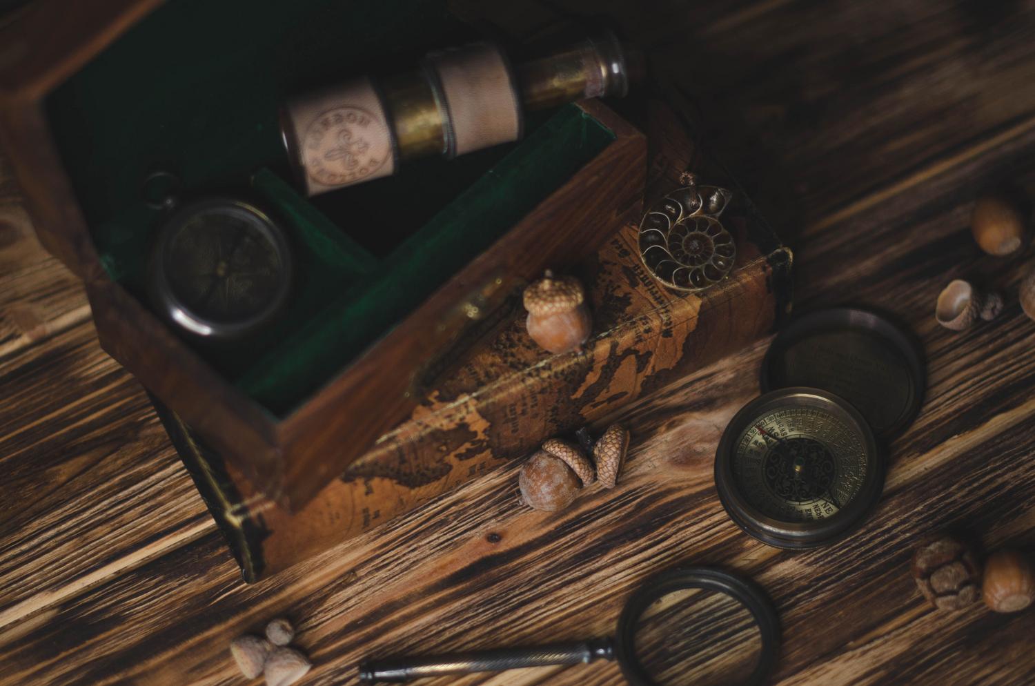 Conjunto de herramientas de explorador y coleccionables sobre una mesa de madera, simbolizando la preparación y las misiones de recolección.