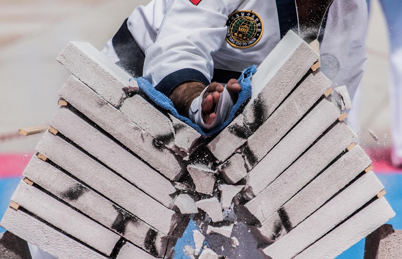 Impacto preciso de un golpe de karate rompiendo tablas de madera, representando la habilidad de Urshifu para atravesar protecciones y defensas.