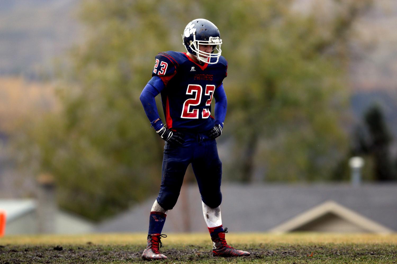 Atleta de fútbol americano con el uniforme manchado de barro, reflejando el esfuerzo y el camino desde los comienzos humildes hacia el estrellato.