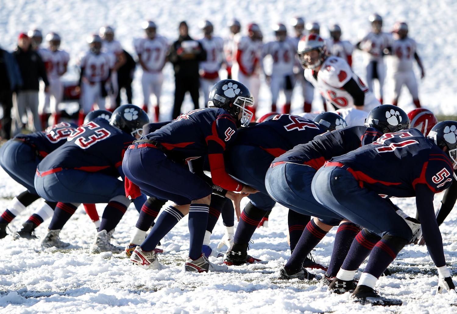 Jugadores de fútbol americano compitiendo en un campo nevado, destacando la mecánica de clima dinámico del juego.
