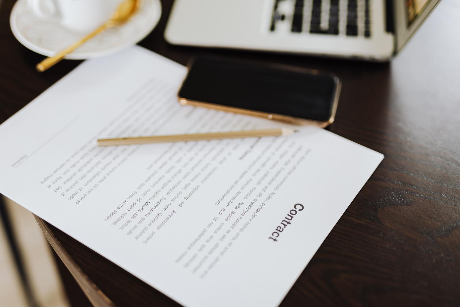 Un smartphone colocado sobre un contrato impreso en un escritorio, simbolizando la intersección entre los acuerdos legales y el uso de la propiedad digital.