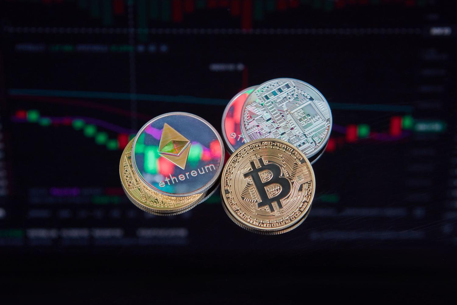 Monedas físicas de Bitcoin y Ethereum sobre un fondo de gráficos financieros, representando los activos digitales con valor económico. Monedas físicas de Bitcoin y Ethereum sobre un fondo de gráficos financieros, representando los activos digitales con valor económico.