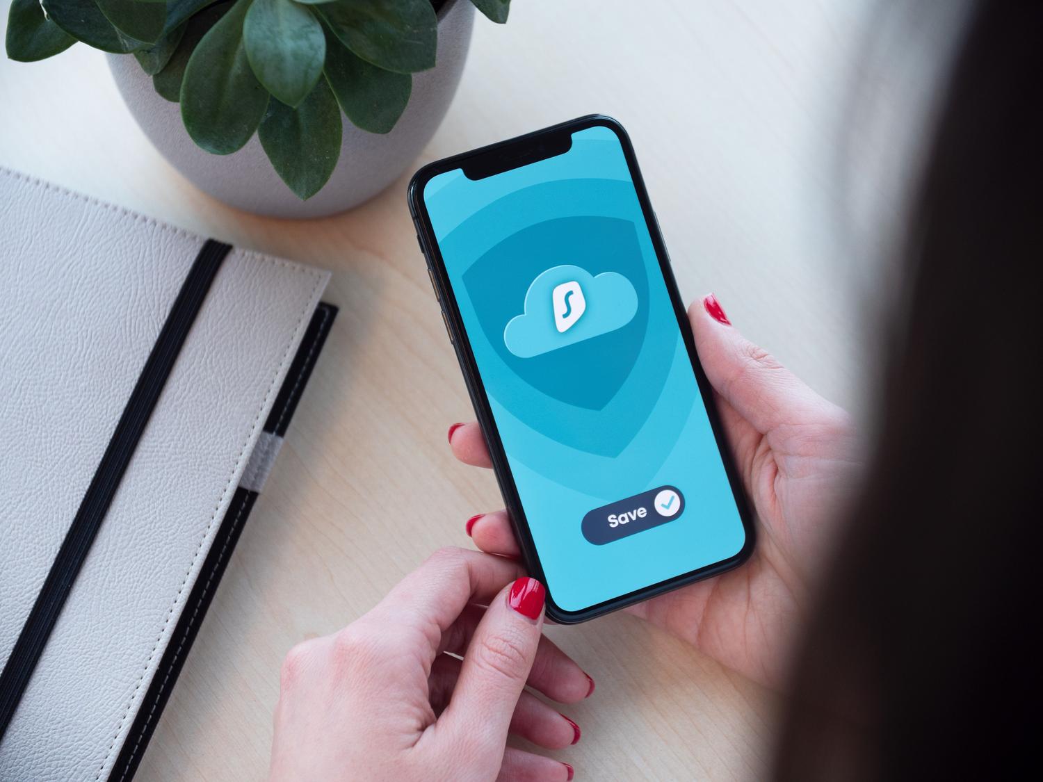 Persona utilizando una aplicación de seguridad en Android que muestra un escudo protegiendo datos en la nube.