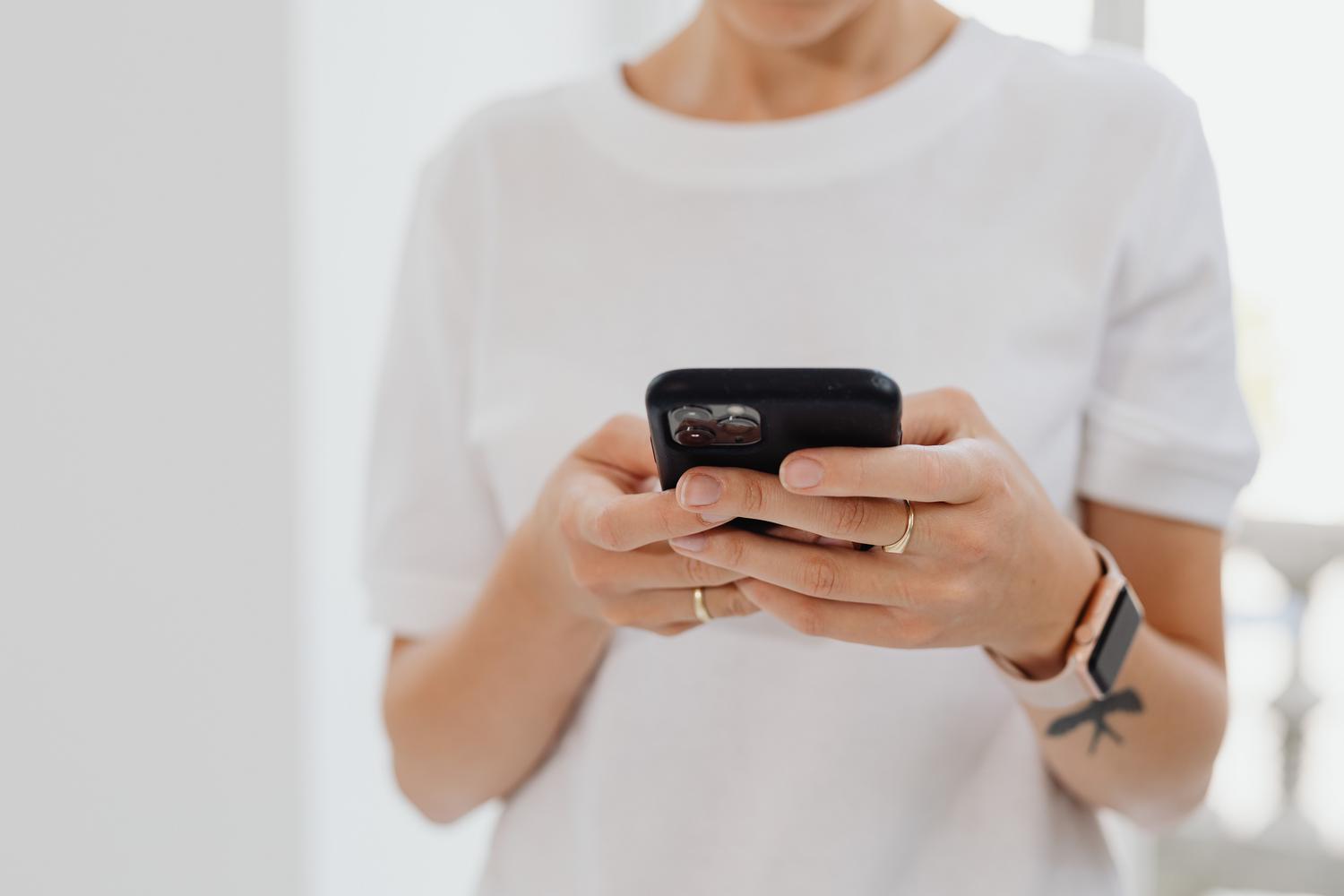 Persona utilizando un smartphone en un entorno profesional, siguiendo los pasos para recuperar una cuenta