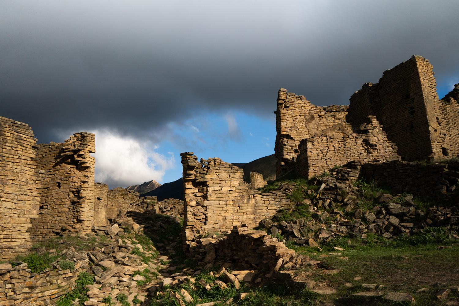 Paisaje de ruinas antiguas bajo un cielo tormentoso, reflejando la estética de fantasía oscura de Nodus Fall
