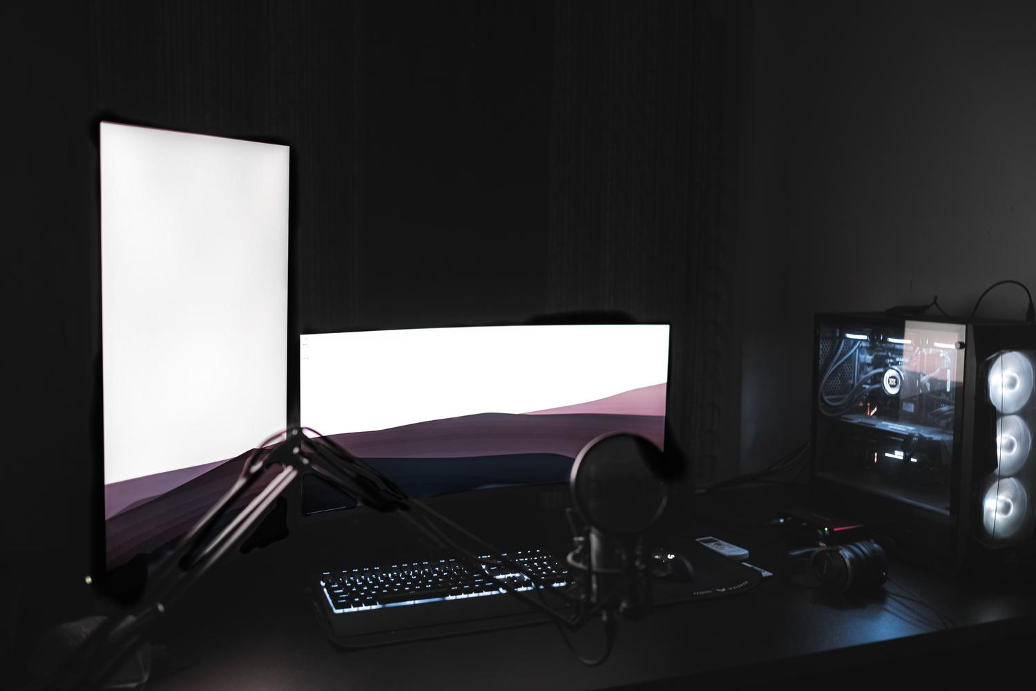 Configuración de PC gaming con monitores brillantes en una habitación oscura, ideal para juegos de terror.