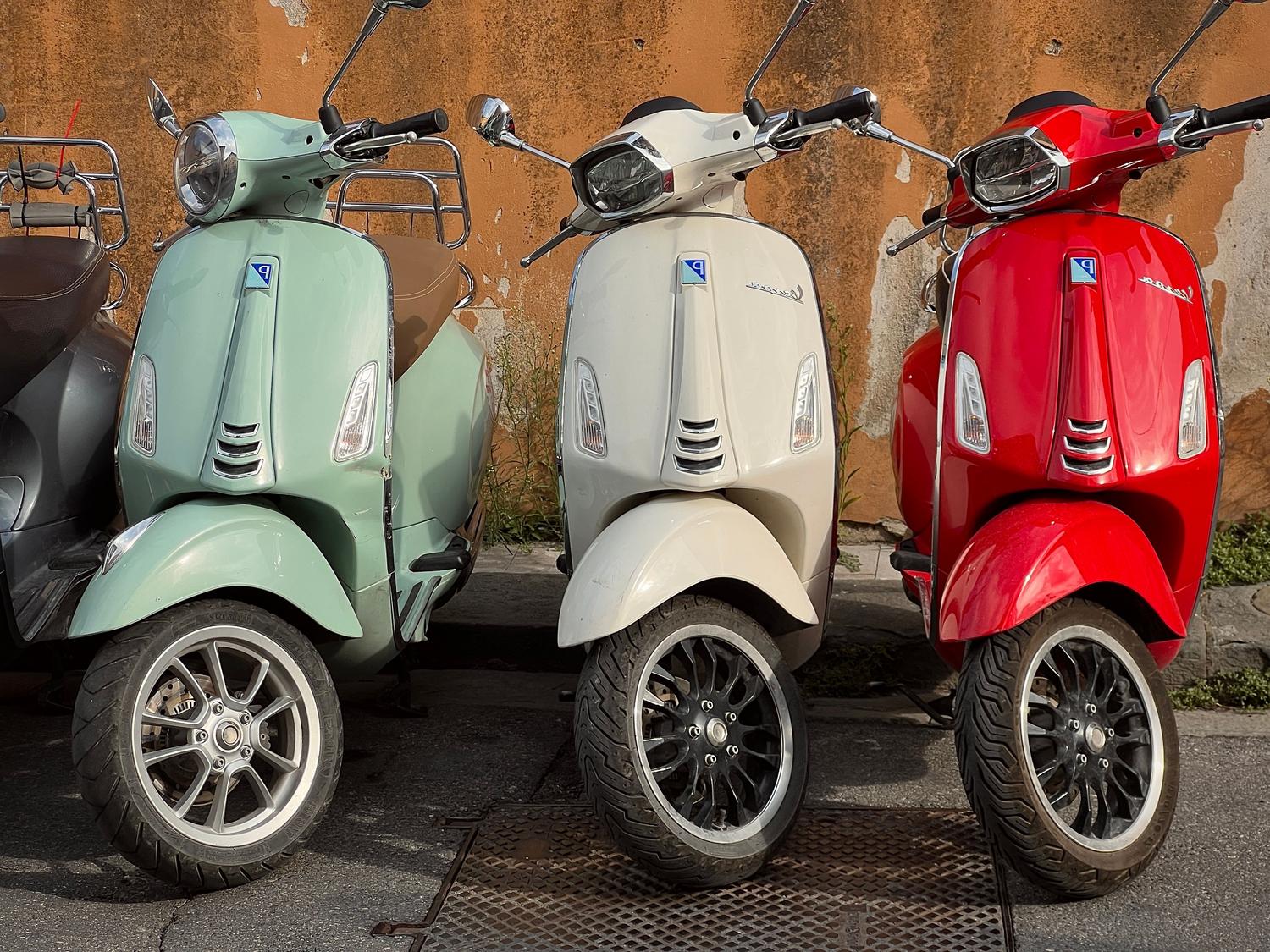 Scooters de estilo retro en colores pastel aparcados contra una pared texturizada, representando la elegancia y el diseño clásico.