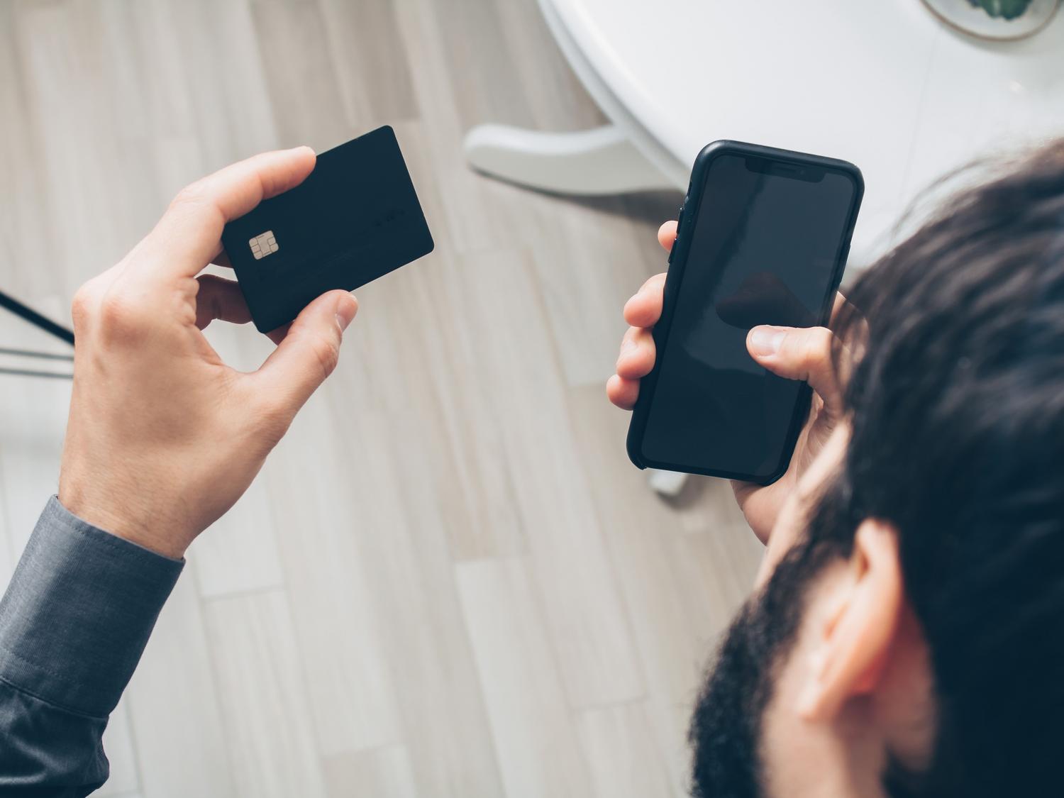Persona sosteniendo un smartphone y una tarjeta de crédito para realizar un pago en línea