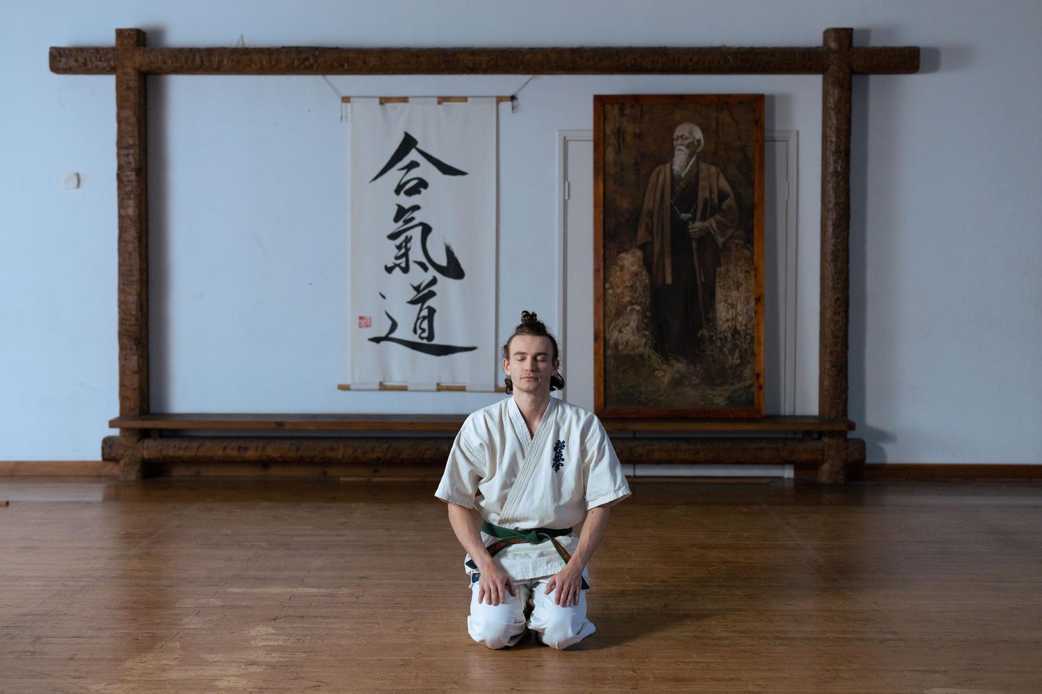 Hombre meditando pacíficamente en un dojo, simbolizando la redención, la paciencia y el juramento de no violencia de la protagonista Tomoe.