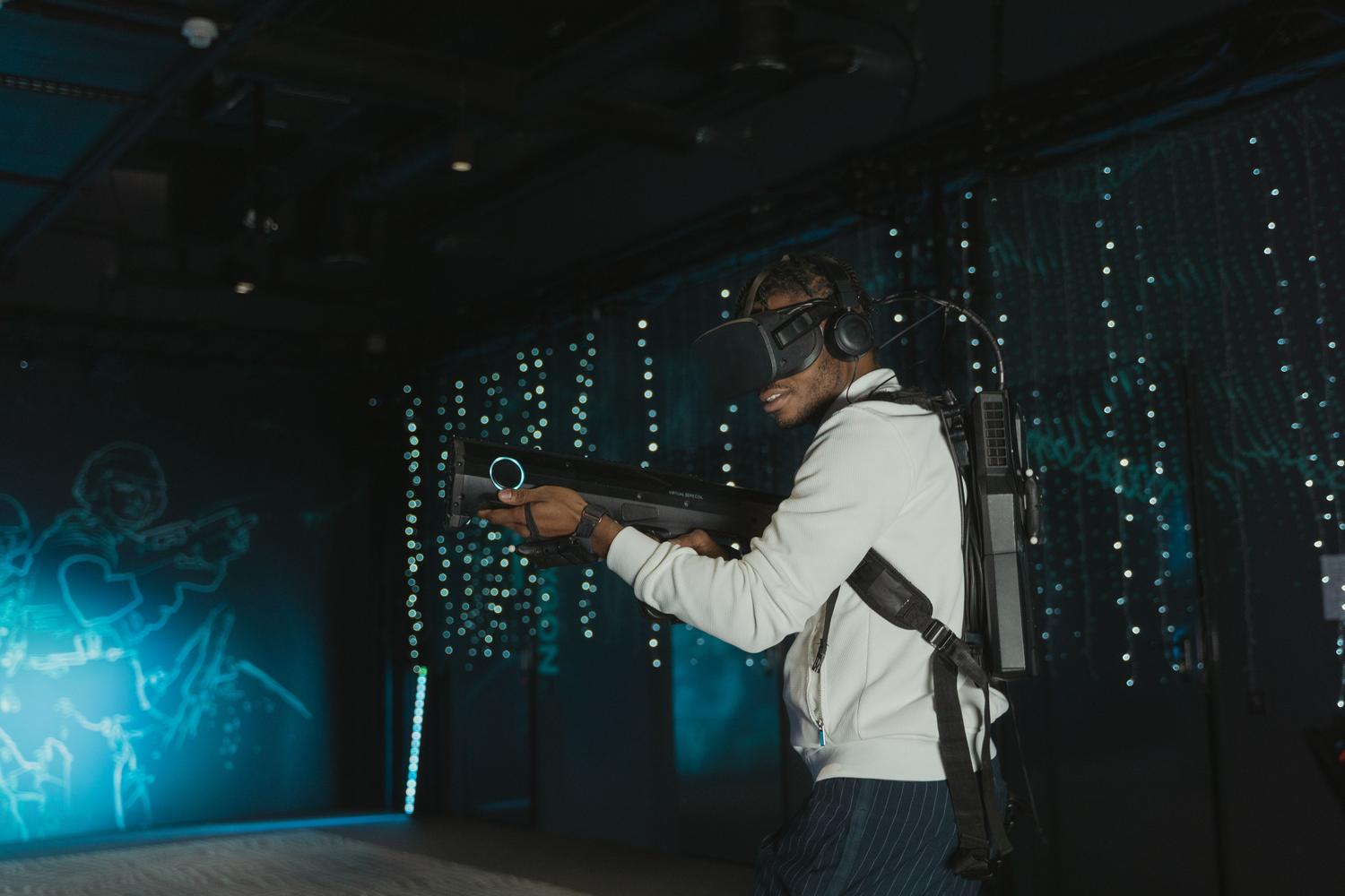 Un jugador utilizando un casco de realidad virtual y un rifle de simulación, representando la experiencia de juego inmersiva.