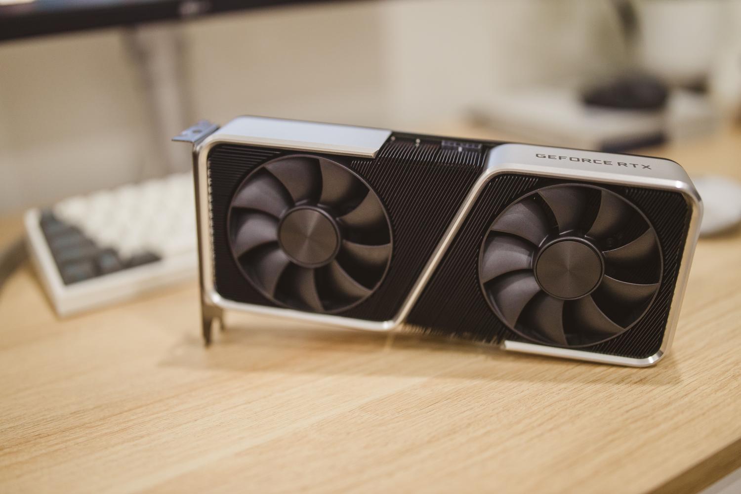 Professional shot of an NVIDIA GeForce RTX graphics card on a wooden desk in a gaming environment.