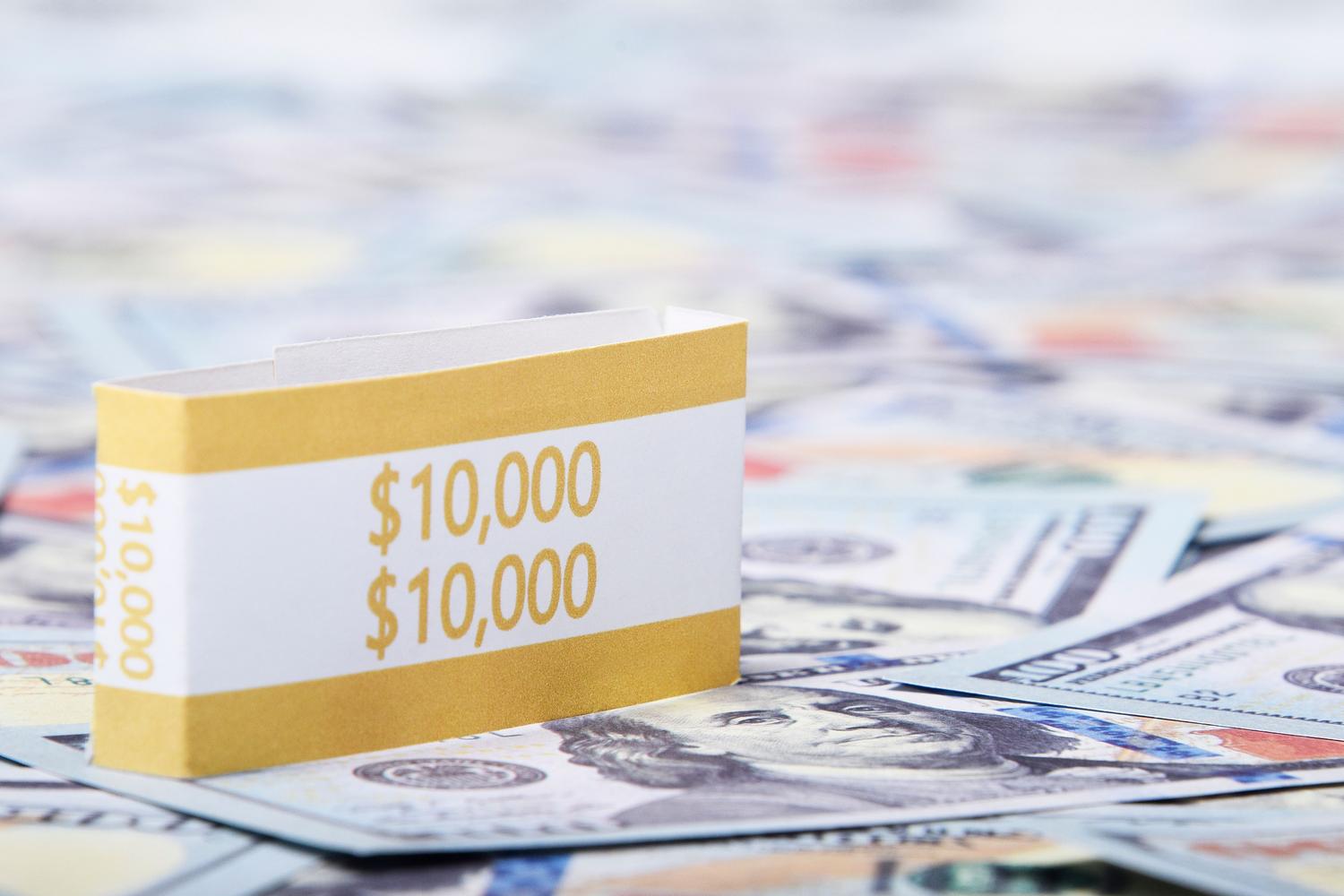 Primer plano de fajos de billetes de dólares estadounidenses, ilustrando el truco de dinero ilimitado.