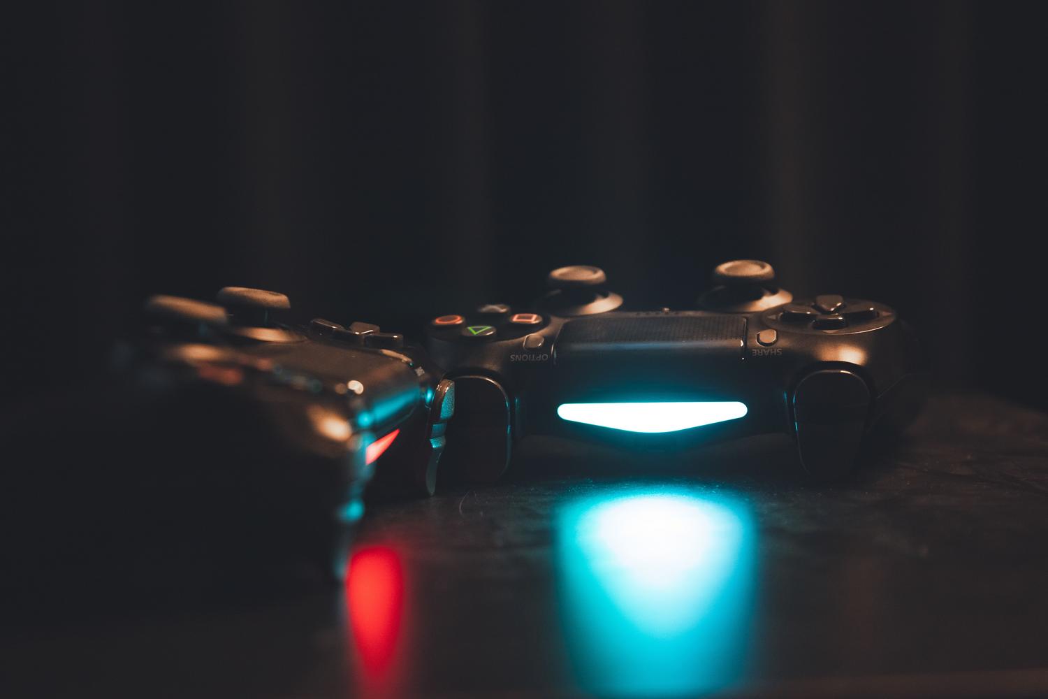 Controladores de videojuegos iluminados sobre una superficie oscura, simbolizando la activación de trucos en el juego.