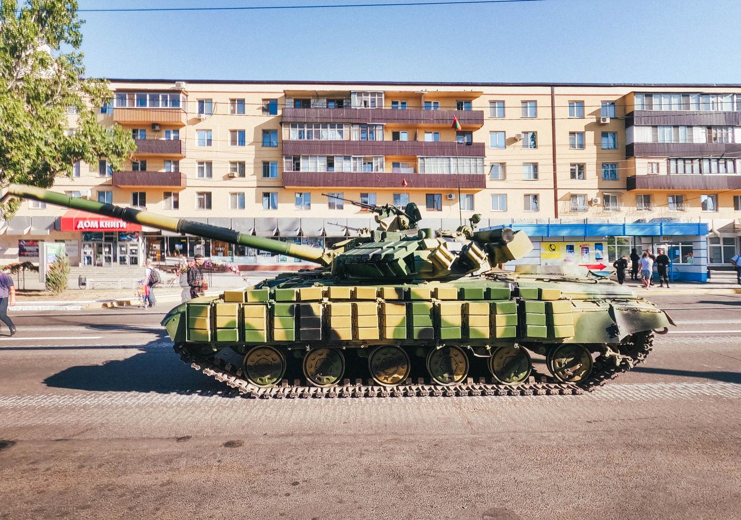 Tanque militar camuflado estacionado en una calle residencial, representando la aparición del tanque Rhino.
