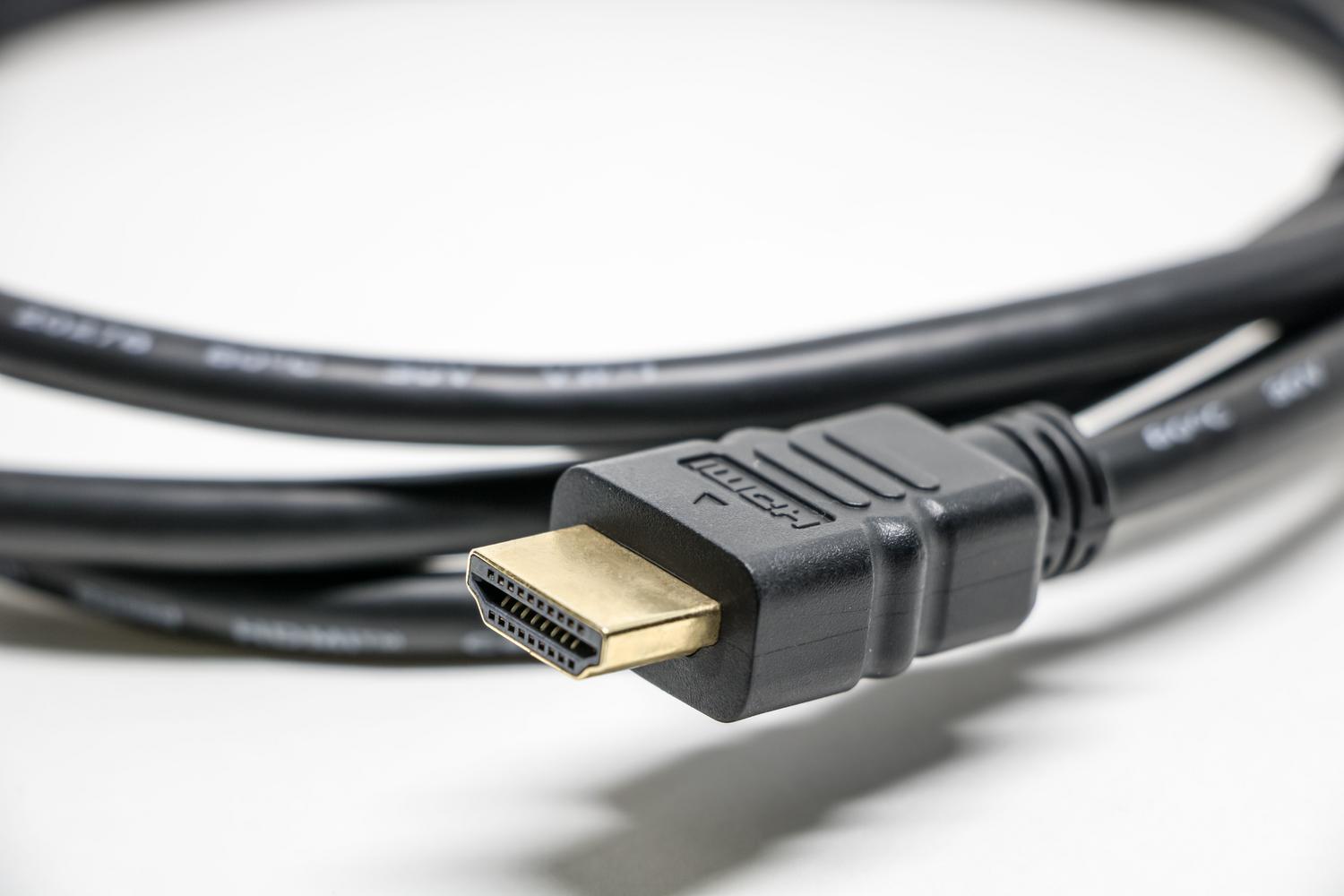Primer plano detallado de un conector de cable HDMI con pines dorados sobre fondo blanco.