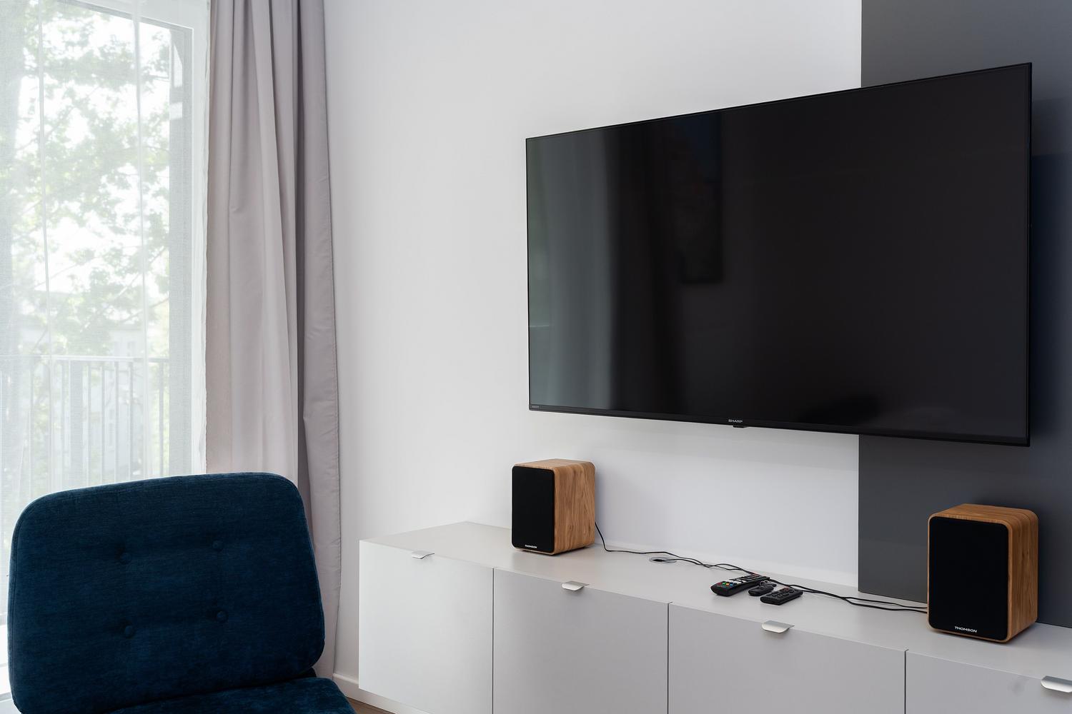 Configuración de cine en casa con televisor montado en la pared y altavoces estéreo de alta calidad.