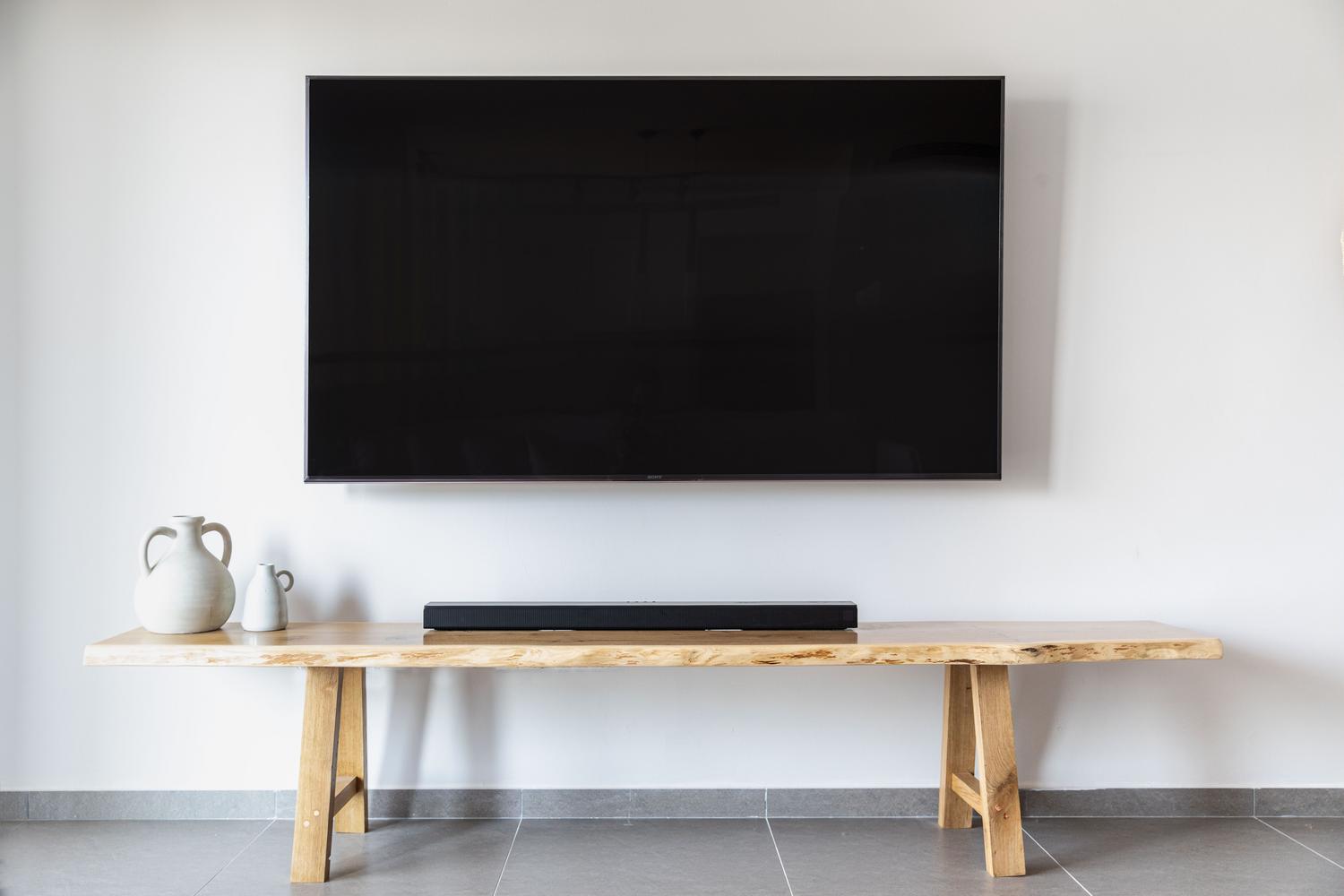Salón moderno con televisor de pantalla plana y barra de sonido instalada debajo.