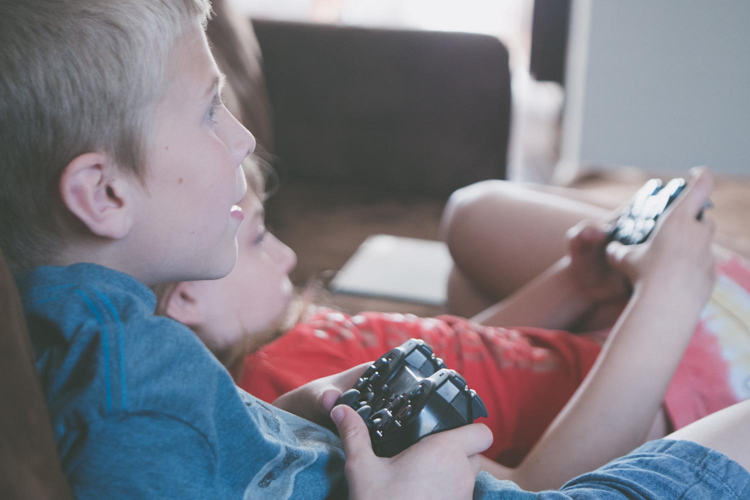 Dos niños jugando videojuegos concentrados en un sofá, representando la diversión accesible de Pokémon Champions Junior.