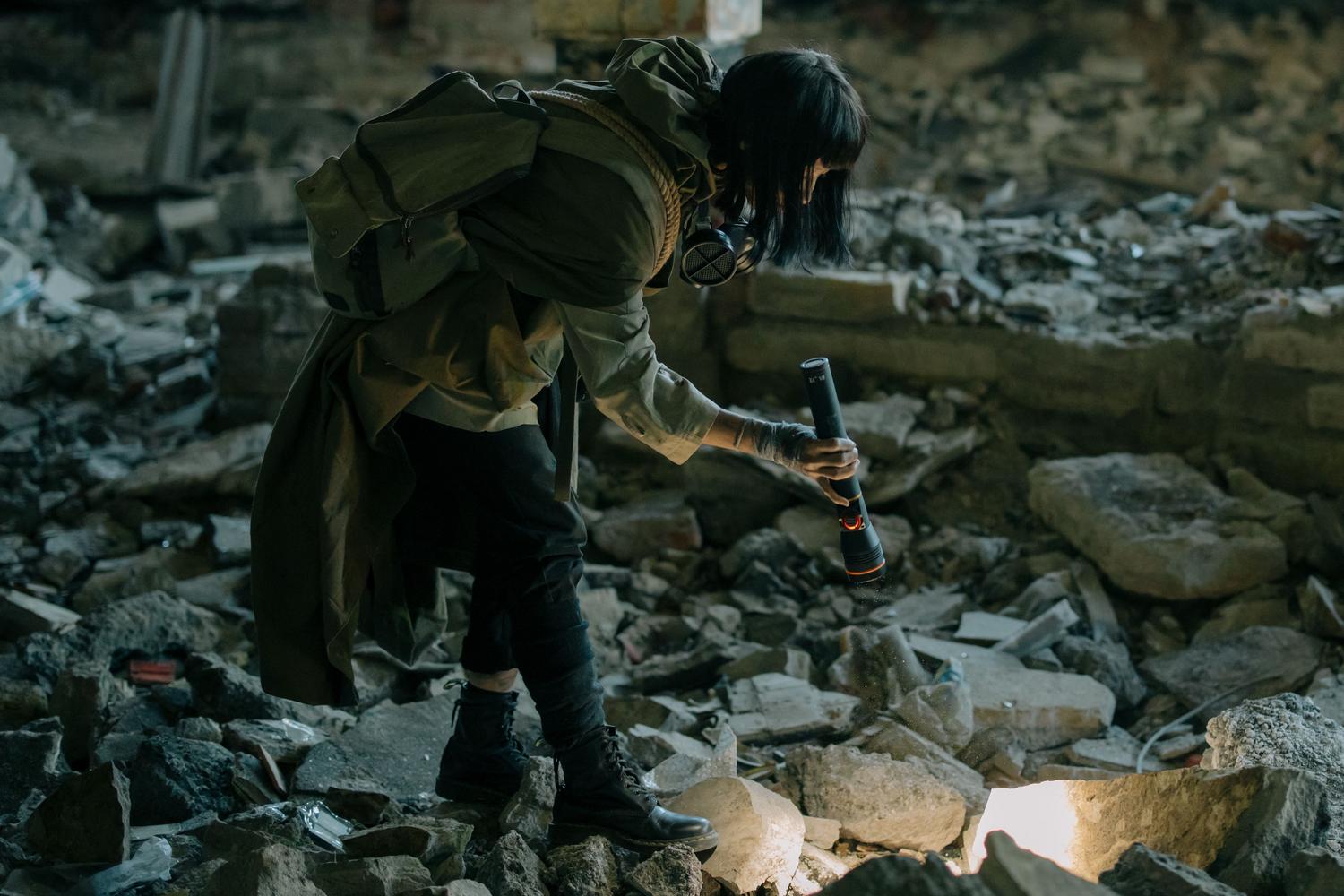 Exploración de ruinas urbanas con linterna en un entorno oscuro y devastado