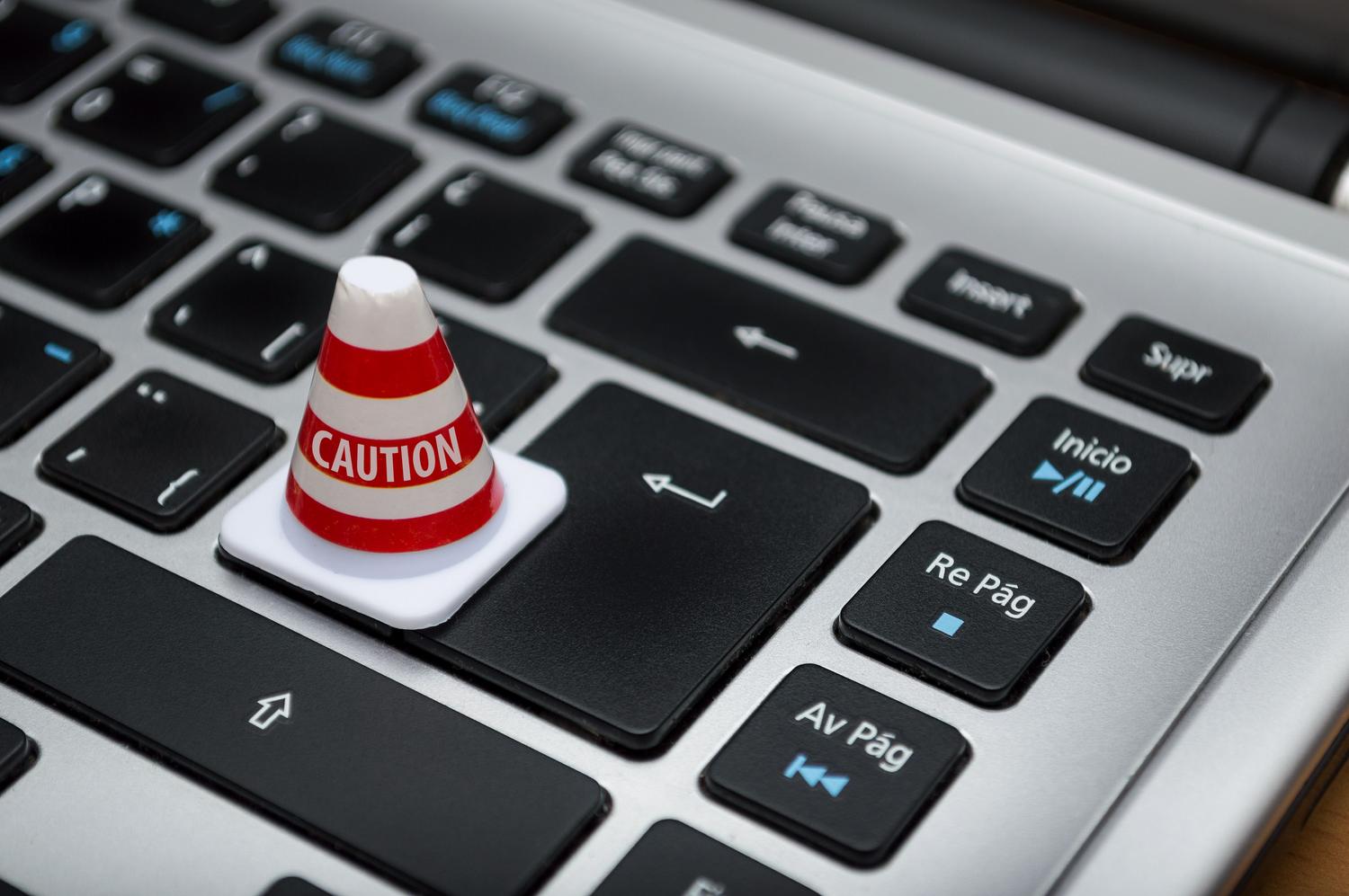 Un mini cono de precaución colocado sobre el teclado de un portátil, simbolizando la alerta ante malware y troyanos.