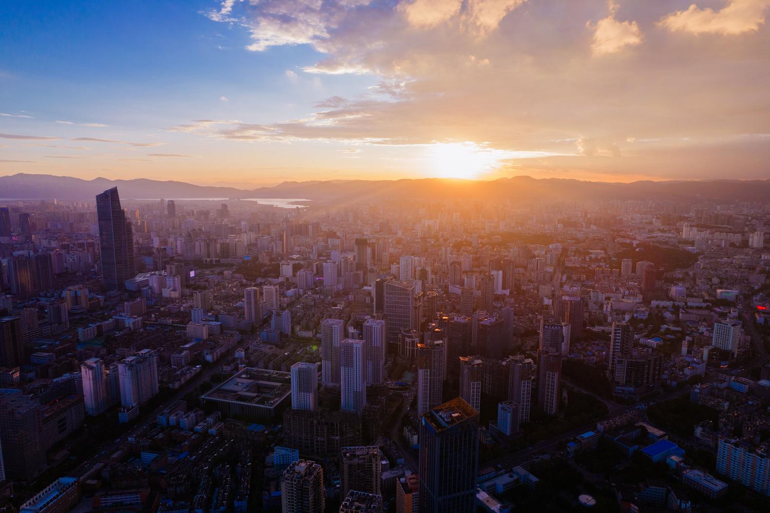 Vista aérea de una metrópolis moderna con rascacielos durante el atardecer.